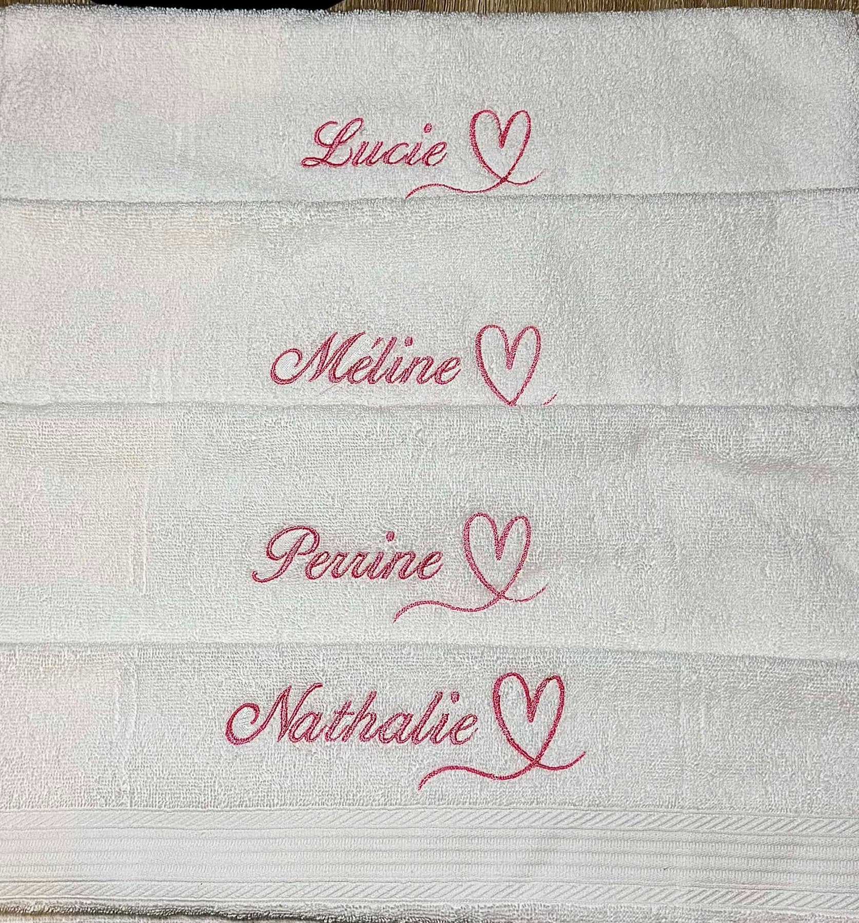 Serviettes blanches avec des prénoms et des cœurs brodés en rose