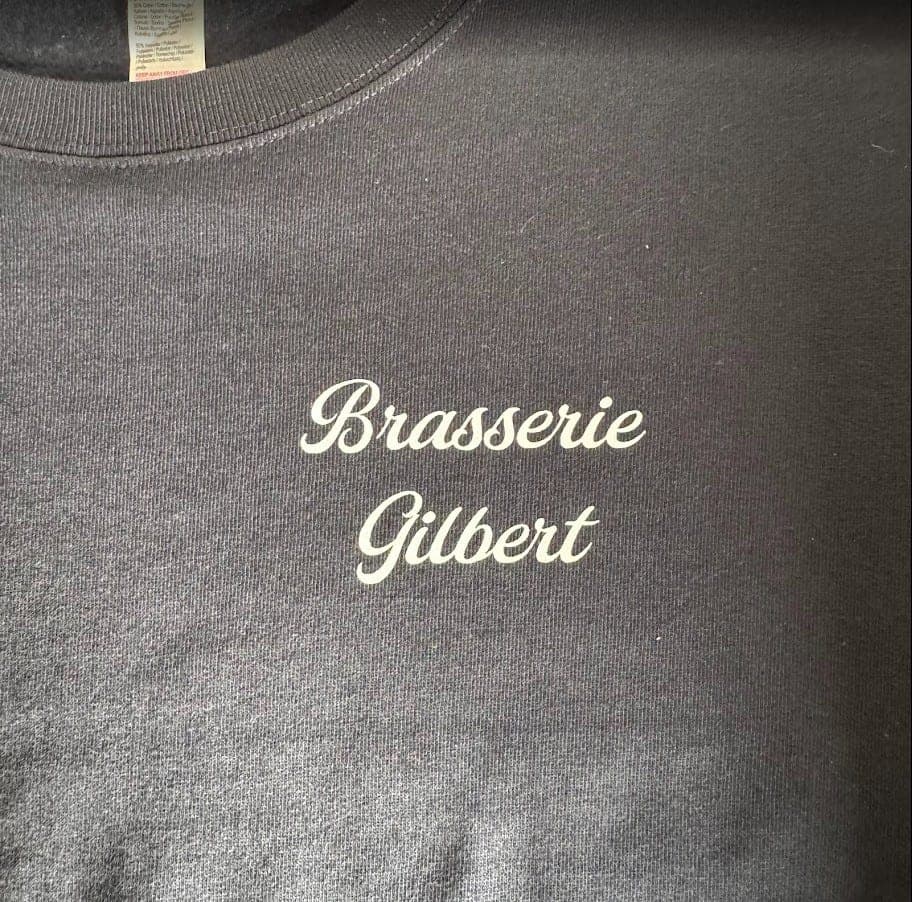 Sweat gris foncé avec un nom en écriture cursive blanche floquée