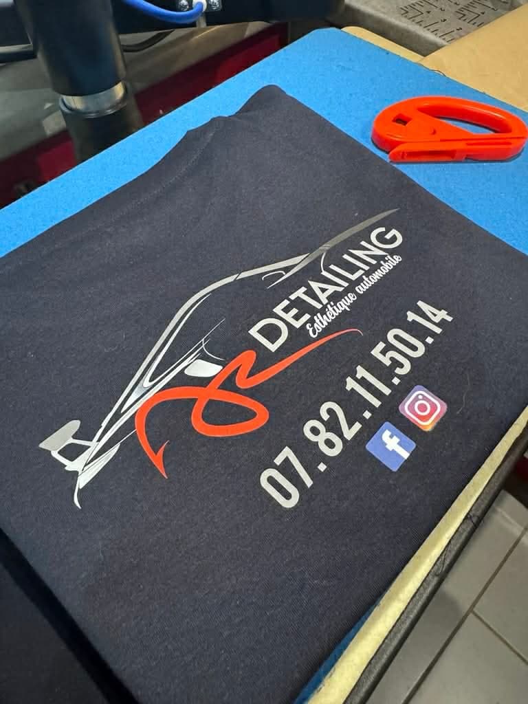 Tee-shirt marine avec un logo imprimé et des coordonnées, posé sur l'établi