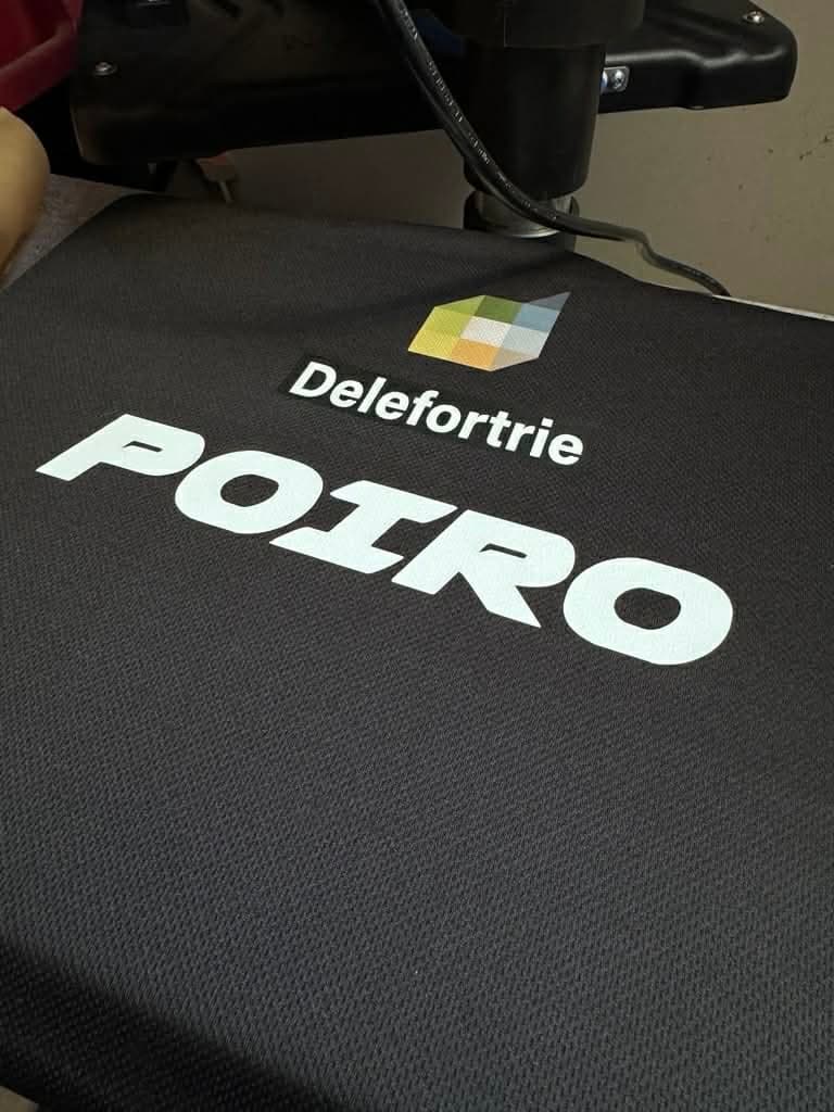 Tee-shirt noir avec un logo et un nom imprimés en blanc, sur la presse