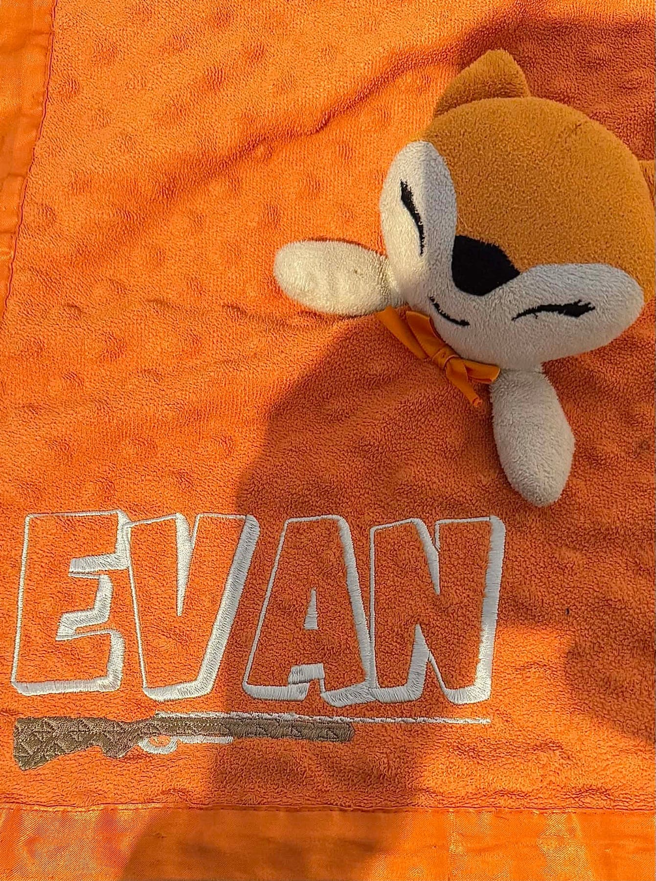 Couverture orange avec un prénom brodé en lettres blanches