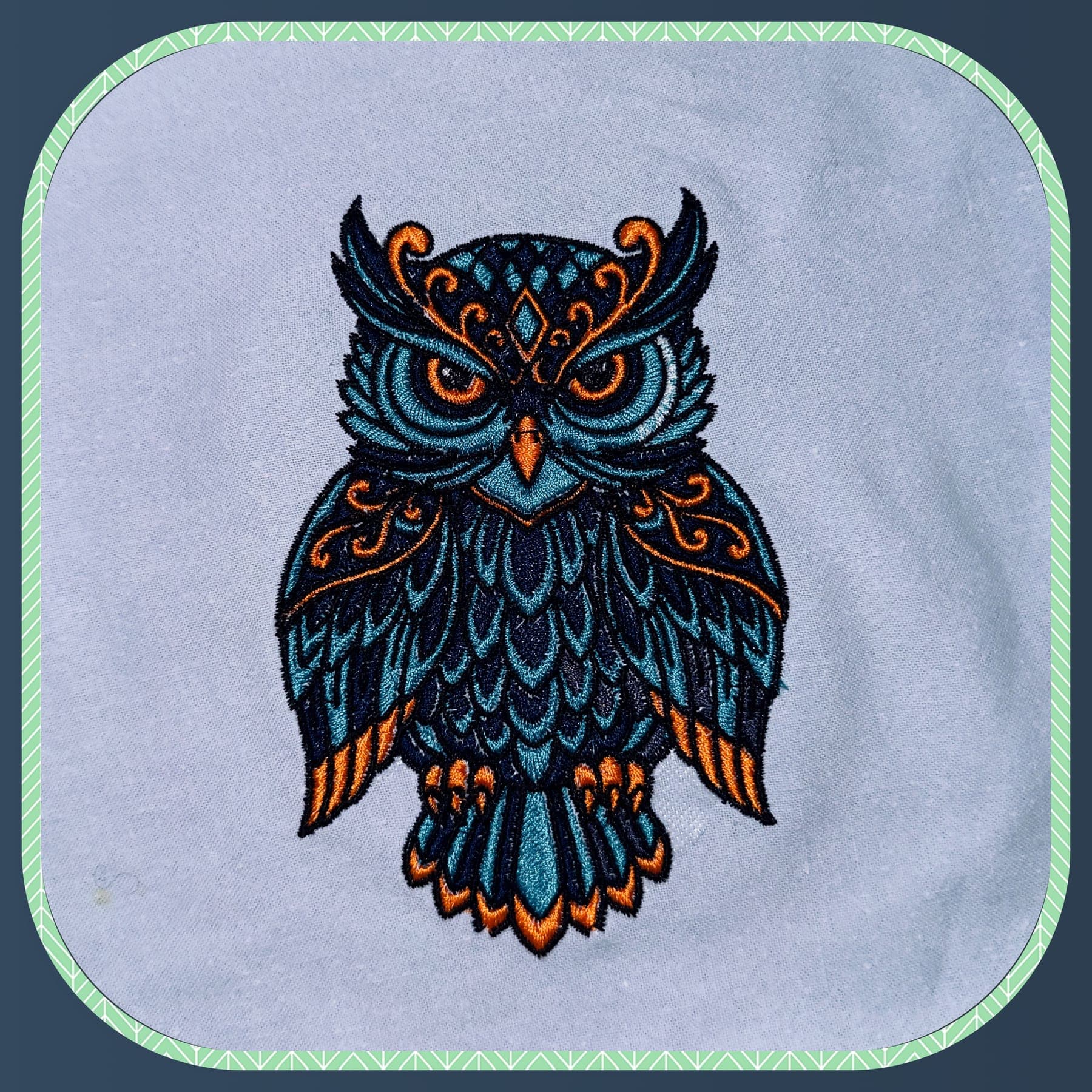 Broderie colorée d'un hibou sur tissu clair