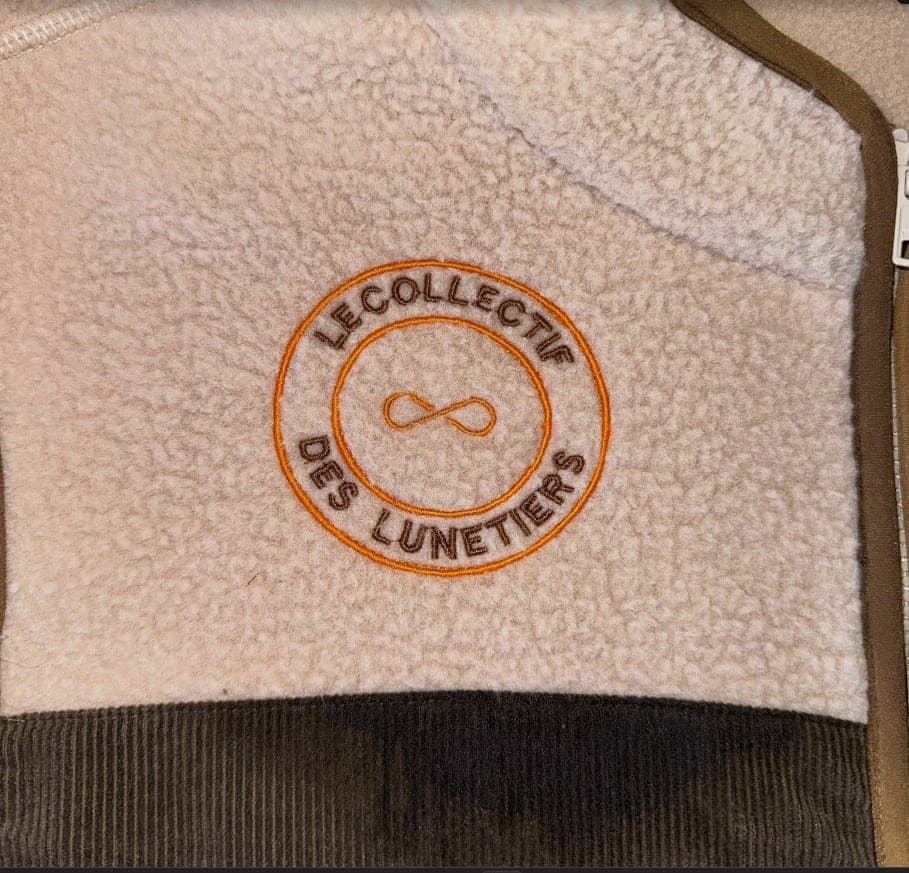Logo circulaire brodé en fil orange sur une polaire beige